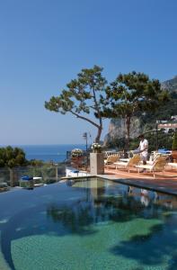 a man sitting on a chair next to a swimming pool at Casa Morgano in Capri