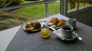 a table with two plates of pastries and a cup of orange juice at Hotel Los Historicos in Villa Gesell +29 photos