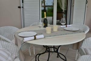 een witte tafel met glazen en wijnflessen erop bij Ktima Grammeno Beachside Villa in Palaiochóra