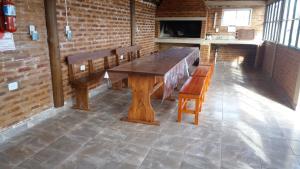 une table en bois et des bancs dans une pièce avec un mur en briques dans l'établissement Cabañas DAYMA, à Trapiche