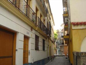 an alley with buildings and a car on a street at RentalSevilla Gran apartamento en Barrio Santa Cruz Parking Gratuito in Seville