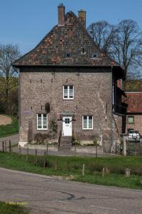 une vieille maison en briques avec une porte blanche dans l'établissement B&B Einrade, à Vaals