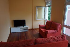 Una sala de estar con dos sillas rojas y un televisor. en Duplex Ribadeo, en Ribadeo