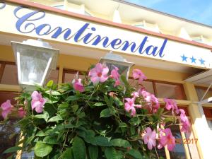 un cartel en un edificio con flores rosas delante en Hotel Continental, en Lido di Jesolo