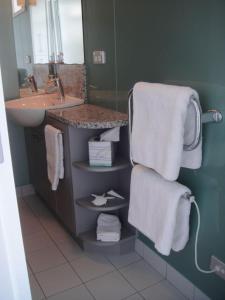 a bathroom with a sink and a counter with towels at Oneroa Bay Villas in Oneroa