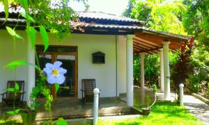 een klein huis met een blauwe bloem ervoor bij River Retreat Sigiriya in Sigiriya