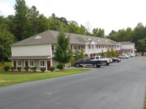 a large house with cars parked in a parking lot at Affordable Suites Salisbury in Salisbury