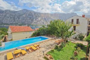 a villa with a swimming pool and mountains in the background at Apartments Feral in Kotor
