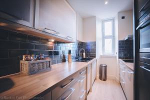 a kitchen with a wooden counter top and black tiles at Impressive 3 bedroom in Aberdeen