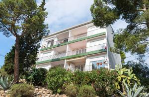 a large white building with trees and plants at Azteka Blue 2 Bed Apartment Calella de Palafrugell in Calella de Palafrugell