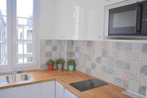 eine Küche mit einer Arbeitsplatte mit einer Spüle und einer Mikrowelle in der Unterkunft Longchamp Apartment in Paris