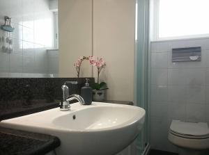 a bathroom with a white sink and a toilet at Overlooking the blue sea in Rafina +28 photos