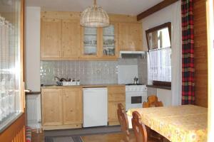 a kitchen with wooden cabinets and a table with chairs at Casa Monteggia in Dobbiaco