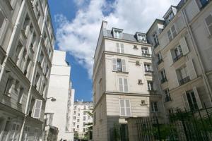 wysoki biały budynek obok dwóch wysokich budynków w obiekcie Longchamp Apartment w Paryżu