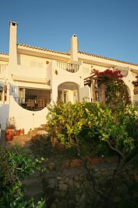 una gran casa blanca con arbustos delante en Casa Ranita, en Marbella