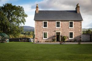 uma grande casa de tijolos com um jardim de relva em Kilmaronock Manse B&B em Drymen