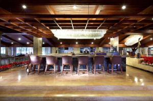eine Bar in einem Restaurant mit einer Gruppe von Hockern in der Unterkunft Dominican Fiesta Hotel in Santo Domingo
