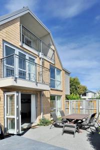 基督城的住宿－Regents 94B - Christchurch Holiday Homes，房屋前设有带桌椅的天井。