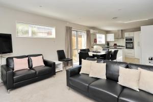 a living room with black leather furniture and a kitchen at Regents 94B - Christchurch Holiday Homes in Christchurch