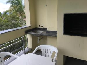 a balcony with a sink and a table and chairs at Residencial Baia Blanca in Florianópolis