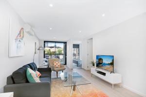 a living room with a couch and a tv at ☆ Heart of St Kilda ☆ Infinity Pool+Parking+WIFI in Melbourne