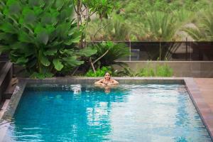 un hombre en una piscina en un resort en Novotel Pekanbaru, en Pekanbaru