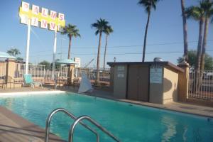 a swimming pool with a hotel sign and palm trees at Palms Inn in Gila Bend