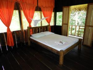 a bed in a room with red curtains at Reserva Natural Tucuchira in Santa Sofía