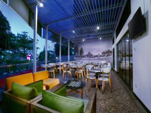 a restaurant with tables and chairs and windows at favehotel Malioboro - Yogyakarta in Yogyakarta