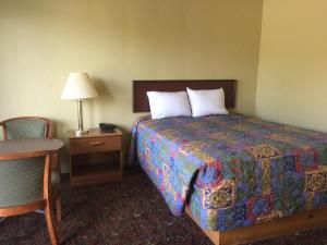 a hotel room with a bed and a lamp and a chair at Quick Stop Motel in Round Prairie