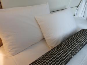 a bed with white pillows and a black and white pillow at Hotel Trusty Osaka Abeno in Osaka