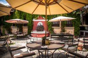 un patio esterno con tavoli, ombrelloni e fontana di Los Olivos Boutique Hotel Antigua Guatemala a Antigua Guatemala