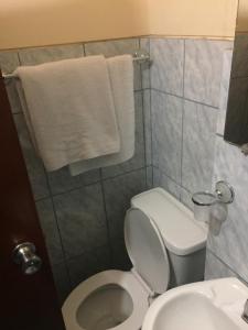 a bathroom with a toilet and a sink and towels at Hotel Cotopaxi in Latacunga