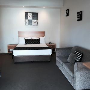 une chambre d'hôtel avec un lit et un canapé dans l'établissement Burkes Hotel Motel, à Yarrawonga