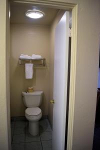 a bathroom with a white toilet and a light at Western Inn & Suites in Taft