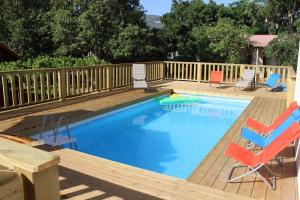 a swimming pool with chairs and a wooden deck at The Wooden Rose Cabins in Beẕet