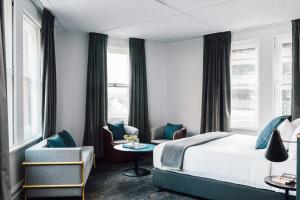 a hotel room with a bed and chairs and windows at Veriu Central in Sydney