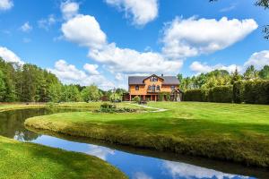 a house on a golf course next to a river at Bražuolėje Pas Juozą- ramiam poilsiui in Trakai