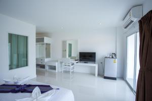 a white room with a bed and a television at White House in Tak