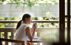 a woman sitting at a table drinking a cup of coffee at Amnaya Resort Kuta in Kuta