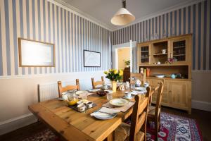uma sala de jantar com uma mesa de madeira com cadeiras em Kilmaronock Manse B&B em Drymen