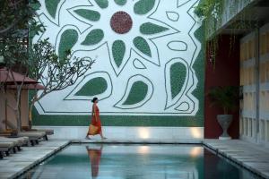 a woman walking by a pool in a building at Amnaya Resort Kuta in Kuta