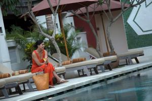 a woman sitting on a bench next to a swimming pool at Amnaya Resort Kuta in Kuta