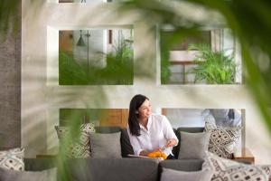 a woman sitting on a couch with a laptop at Amnaya Resort Kuta in Kuta