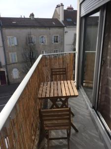 Elle comprend un balcon avec une table et des chaises en bois. dans l'établissement Meublé de Tourisme Au Troubadour, vaste T2 proximité République avec garage, à Dijon