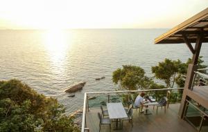 a couple sitting at a table on a balcony overlooking the water at Cliff Lanta Suite-Koh Lanta Krabi in Ko Lanta