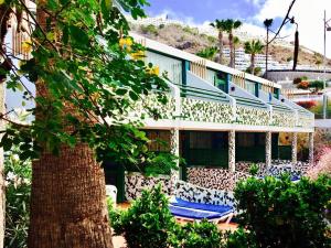 un edificio con sillas azules y un árbol en Leticia del Mar Adults Only, en Puerto Rico de Gran Canaria