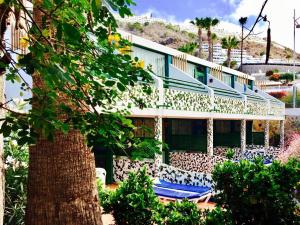 a building with blue chairs and a tree at Leticia del Mar Adults Only in Puerto Rico de Gran Canaria