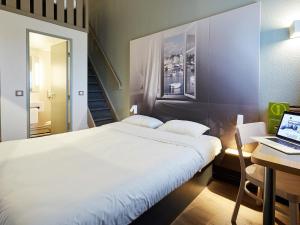 a bedroom with a bed and a desk with a laptop at B&B HOTEL Cherbourg in Cherbourg en Cotentin