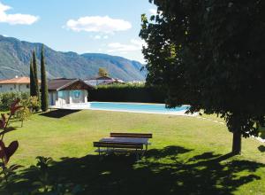 un banc de parc assis dans l'herbe à côté d'une piscine dans l'établissement Ausserdorfer Apartments, à Lana